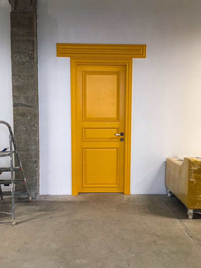 A vibrant yellow wooden door in a minimalist room with concrete elements and neutral colors.